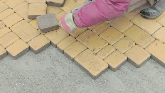 一名建筑工人的手用黄色铺路石做了一条小径。