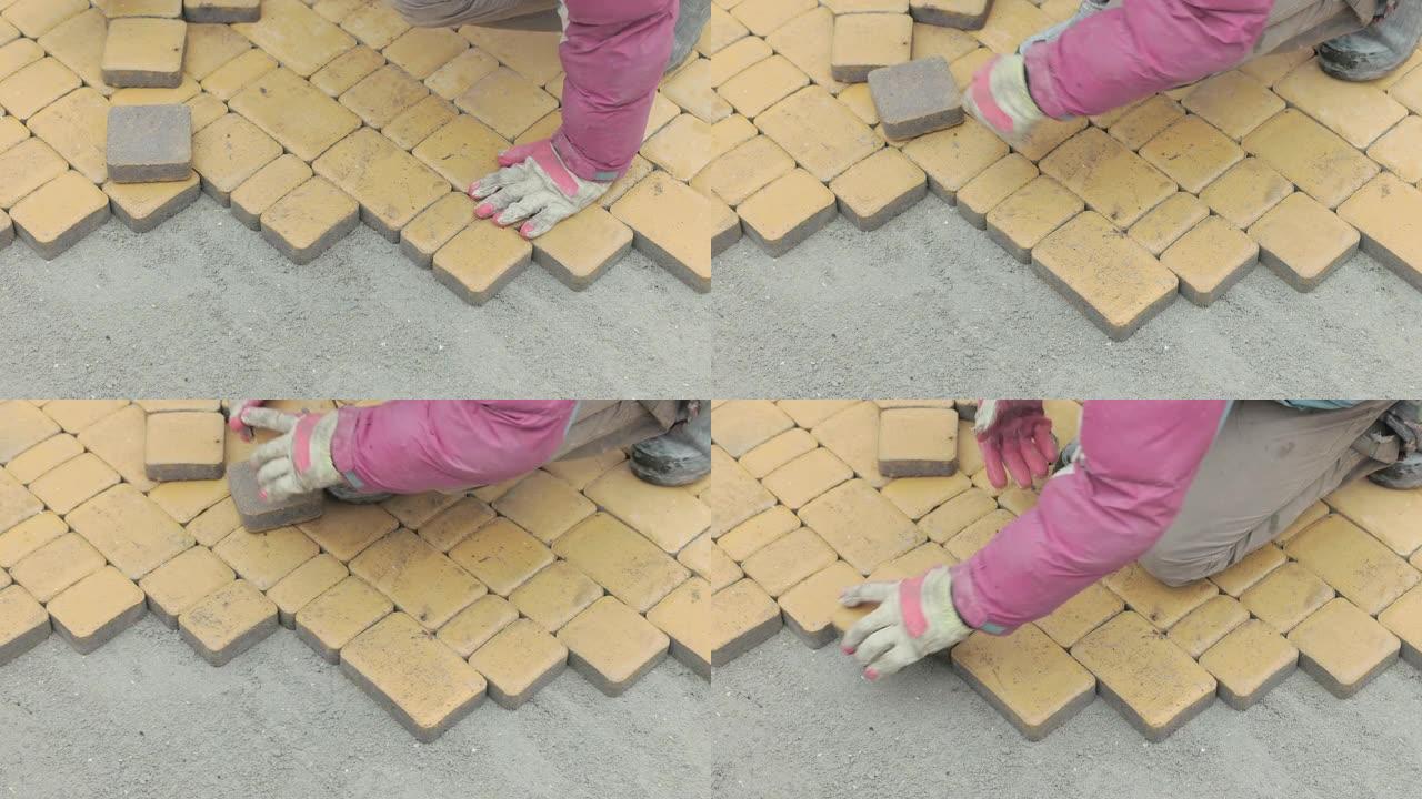 一名建筑工人的手用黄色铺路石做了一条小径。
