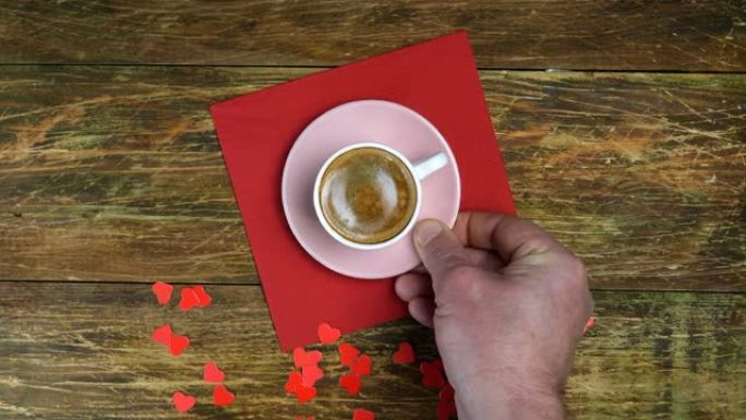 人手将一杯咖啡放在红色餐巾上，并点燃心形蜡烛。浪漫的一天。