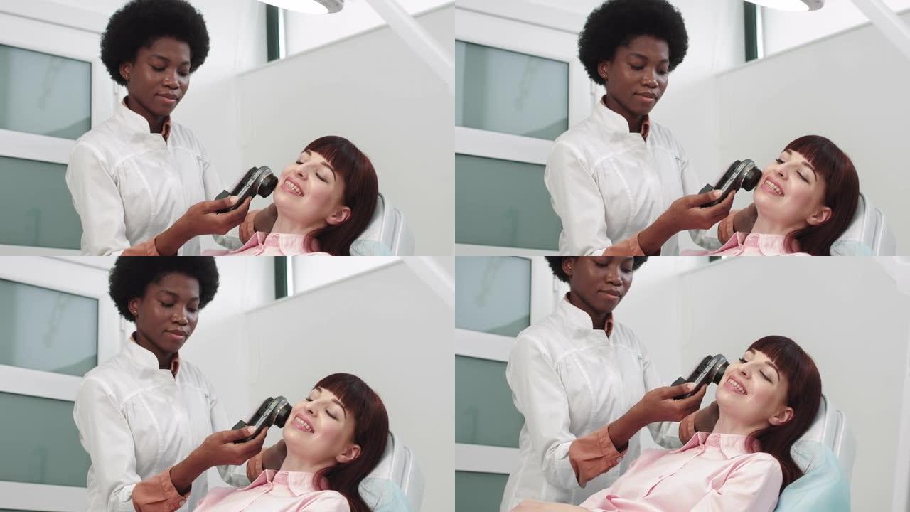医生是非裔美国皮肤科医生检查皮肤。专业医生皮肤科医生研究手机上的胎记连接到特殊的皮肤镜工具。面部检查
