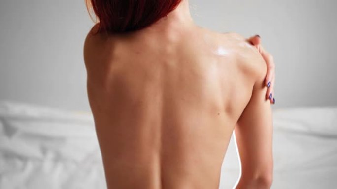 背部苗条的女性在肩膀上涂抹润肤霜