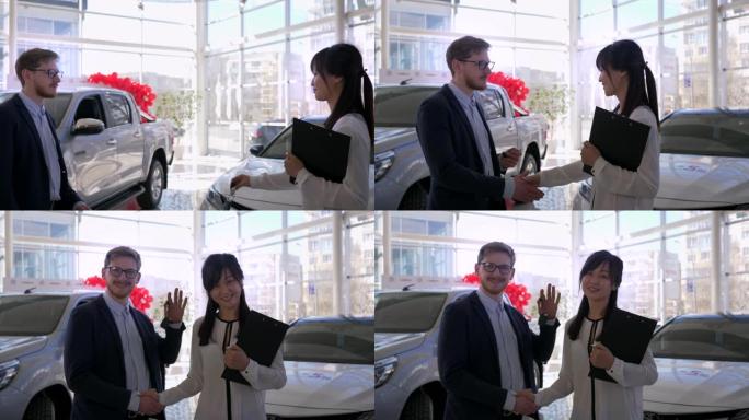 成功购买，在汽车销售中心与客户男子握手和交出汽车钥匙的幸福女人经理肖像