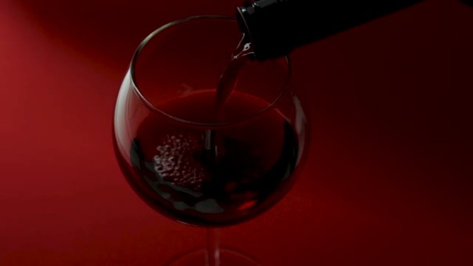 将葡萄酒倒入红色背景上的酒杯特写，红酒在玻璃杯中