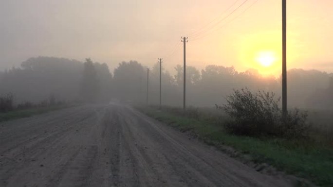 汽车在浓雾中行驶乡村碎石路。秋天早晨的薄雾日出。4K