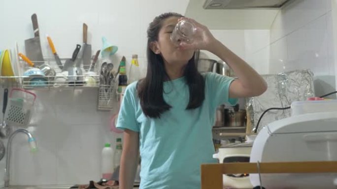快乐的亚洲女孩在家厨房喝一杯水，生活方式理念。
