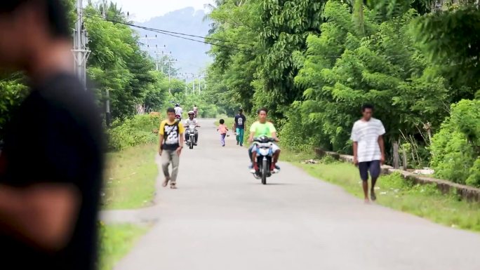 印度尼西亚巴厘岛路边卖食物的街头小贩 路中间有一座清真寺 一个男人站在栅栏前，上面挂着衣服