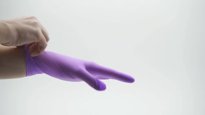 女性手部特写穿着乳胶、丁腈、橡胶、医用手套淡紫色在孤立的白色背景上
