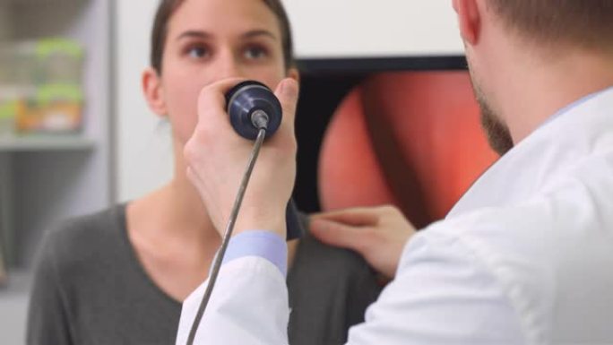用内窥镜检查女性患者的特写男性耳鼻喉科医生