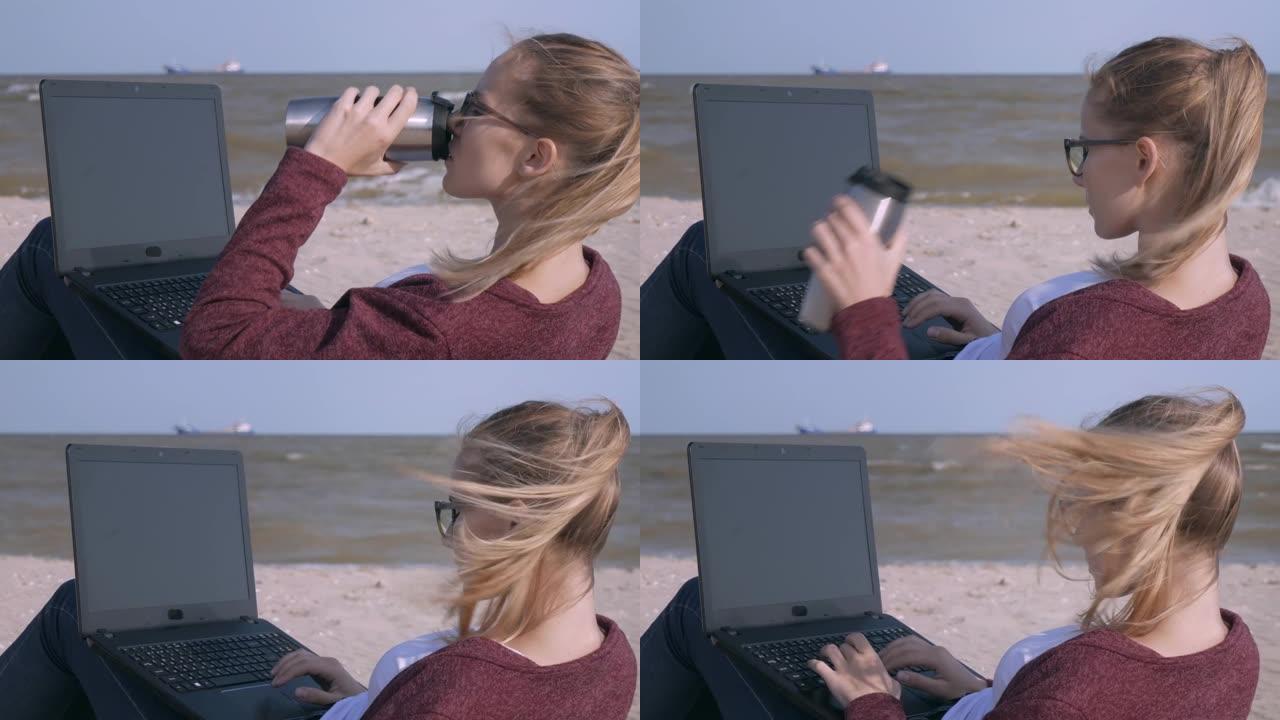 这位年轻帅气的女士一边用笔记本电脑工作，一边在夕阳下的沙滩上喝着咖啡。日落时分，年轻的商人在海滩上工