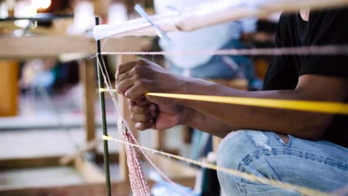 亚洲工人在打领带和染色之前，先织结Mudmee板编织或Ikat Thai丝绸图案编织。