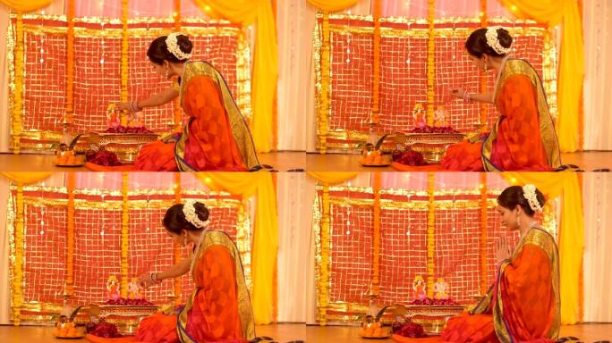 美丽的印度女人把提卡应用到印度教神的偶像上，用namaskar-Pooja背景低头