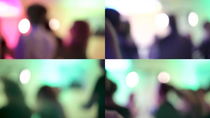 在音乐会或迪斯科舞厅中，在夜总会的舞池中，在五颜六色的聚光灯下，跳舞的人的轮廓模糊。