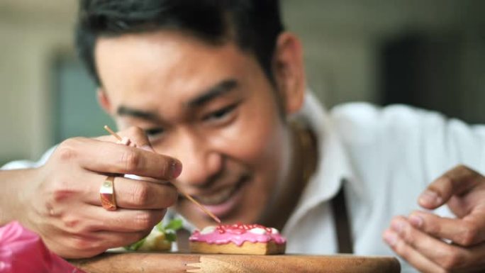 快乐的亚洲男人在家装饰情人节饼干，生活方式理念。