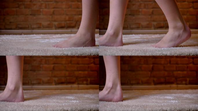 在砖墙背景上的毛茸茸的地毯上，女性双腿的特写镜头缓慢地迈出了脚步。
