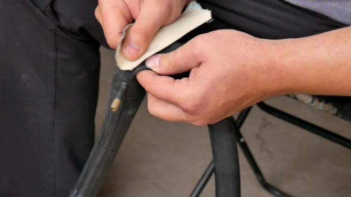 骑自行车的人或机械师清洁轮胎的自行车。手和自行车爆胎的特写。一名男子修理穿孔的自行车车轮。