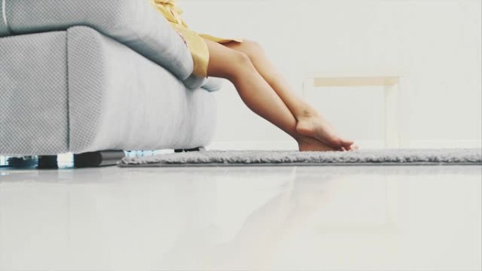 女人的腿在地板上的灰色地毯上行走。从上面看蓬松的地毯。现代风格。