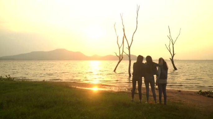 一群年轻女子紧密站在水边看日落