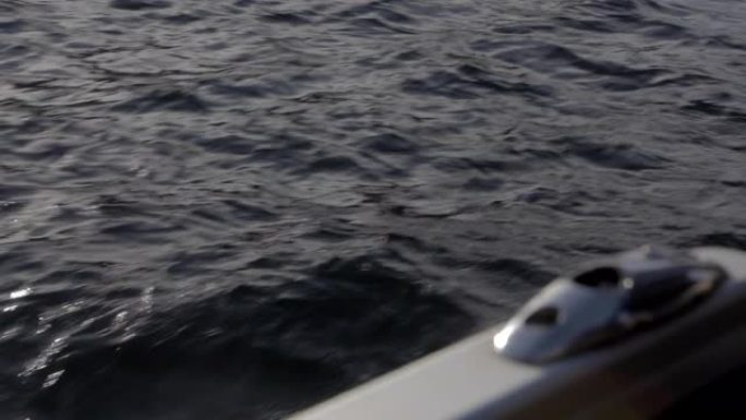 在巴黎一个夏天的下午，在巴黎的一次巡游中，从船的侧面拍摄了蓝色的海。前景为船底漆的小浪。特写4K。