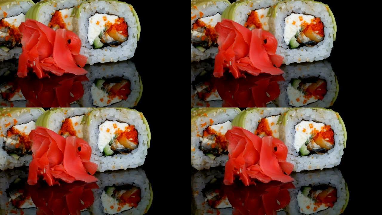 绿龙寿司卷和粉色姜。寿司卷配三文鱼、蔬菜和鳄梨特写。日本餐厅菜单在黑色背景下的镜面上
