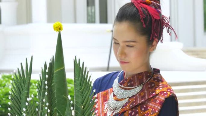 泰国年轻女子穿着泰国民族服装套装拿着花盘。欢迎来到泰国概念。
