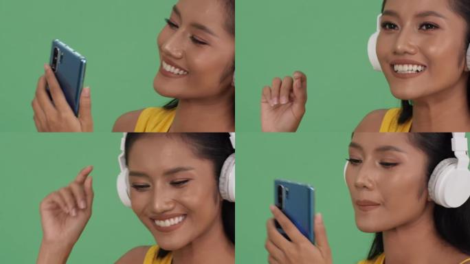 亚洲美女在线听音乐快乐情感微笑。戴着耳机和手持智能手机的女人。美丽、时尚和音乐体验的概念。