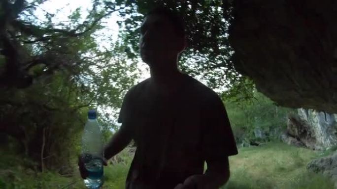 年轻的成年男子晚上带着一瓶水在旷野徒步旅行