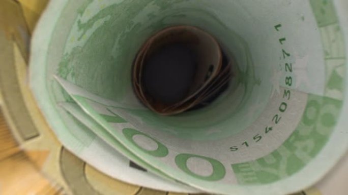 在钱洞里。多莉拍摄的抽象透视欧元纸币卷在管中。多莉拍摄储蓄和投资的概念