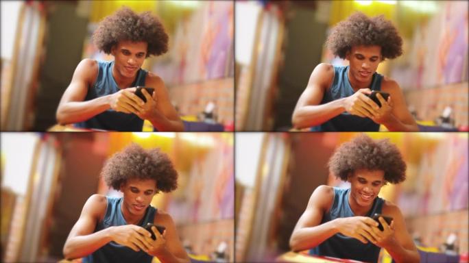 年轻英俊的黑人微笑着在晚上检查手机