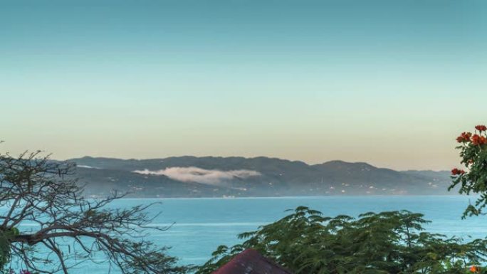在大西洋的蒙特哥湾牙买加的臀部地带，雾气在整个海湾的山丘上滚动，鸟儿飞舞，小船飘过，被水，屋顶和树木