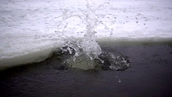 将冰块倒入冰冻的河流中的慢动作