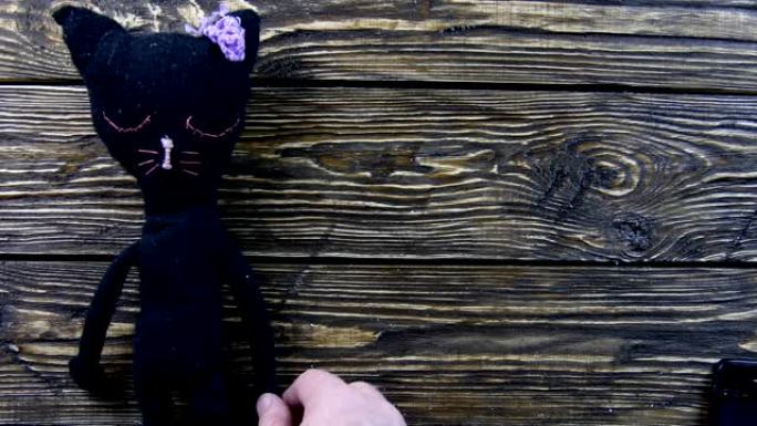 木制背景上的玩具毛绒黑猫