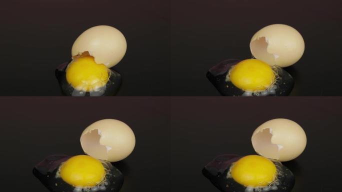 从黑色表面的破碎蛋壳中倒出的蛋黄