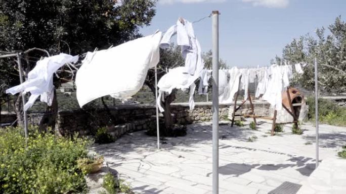 希腊克里特岛户外晾衣绳上的白色衣服在风中干燥