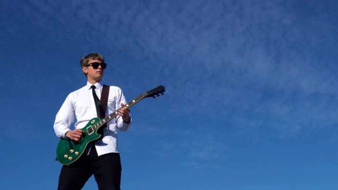 年轻人在蓝天下弹吉他。4k