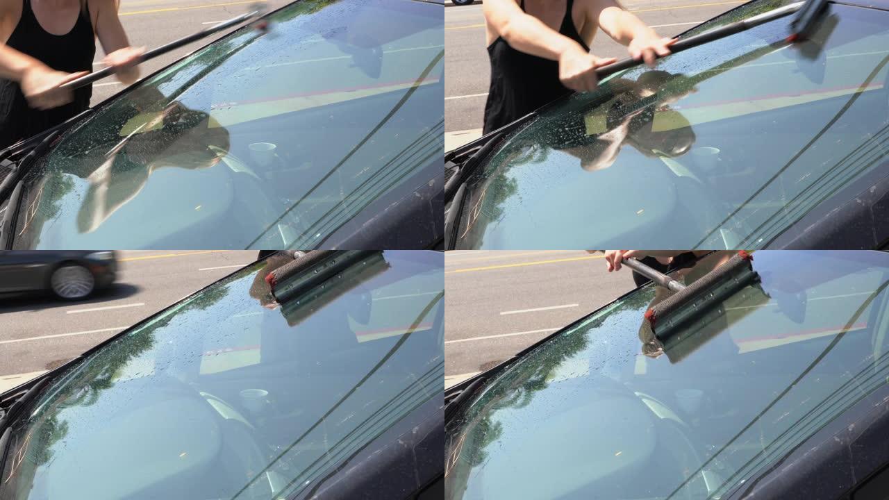 女人用加油站刮板清洗汽车挡风玻璃