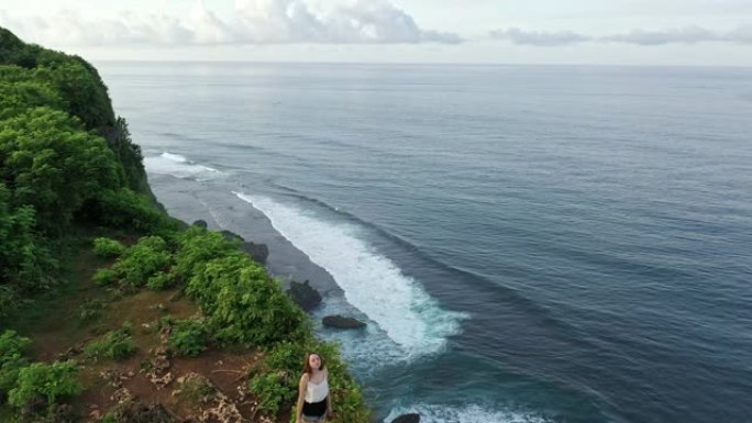 站在悬崖上眺望巴厘岛乌鲁瓦图海边的女人的鸟瞰图