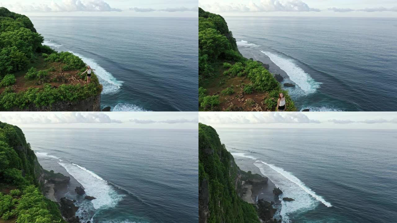 站在悬崖上眺望巴厘岛乌鲁瓦图海边的女人的鸟瞰图