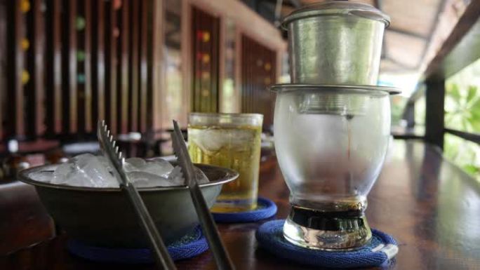 在咖啡馆使用越南传统的phin过滤器酿造黑咖啡。咖啡在玻璃杯中慢慢滴落。Ca phe den da。