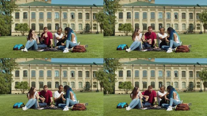 在校园草坪上吃零食的年轻学生