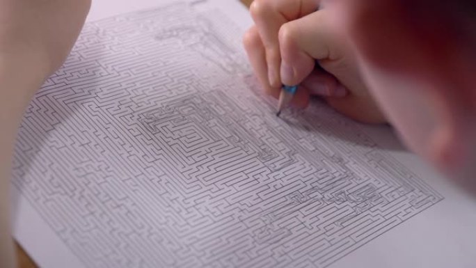 男孩正在家里用铅笔解决纸上印刷的迷宫。