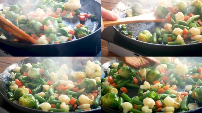 炸肉片和蔬菜在煎锅中用葵花籽油油炸。特写。豆子、胡萝卜、花椰菜