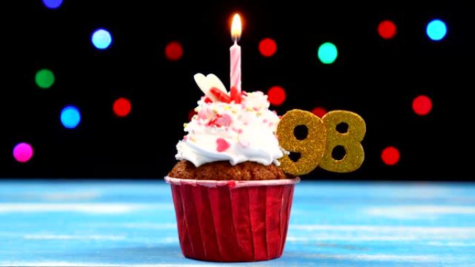 美味的生日蛋糕，蜡烛燃烧，彩色模糊灯光背景上有98号