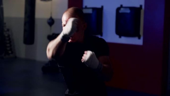 男子拳击手训练在健身房向相机挥拳，在慢动作中进行阴影搏斗。