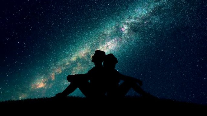 这对夫妇坐在星空背景上的草地上。时间流逝