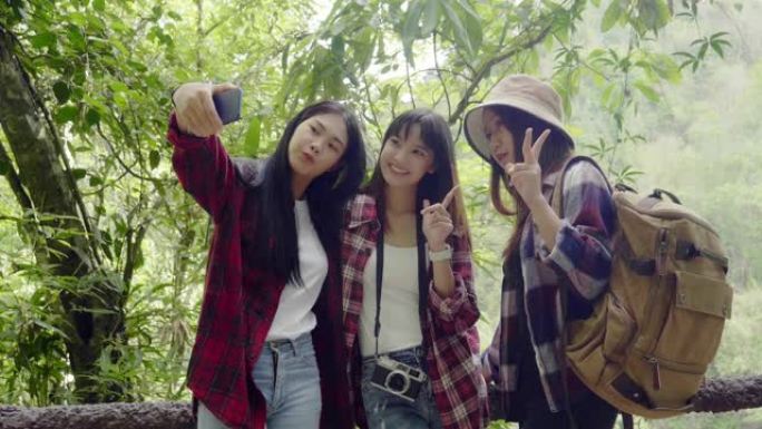 亚洲年轻女孩团体步行旅行自然女孩手持智能手机自拍自然背景看屏幕