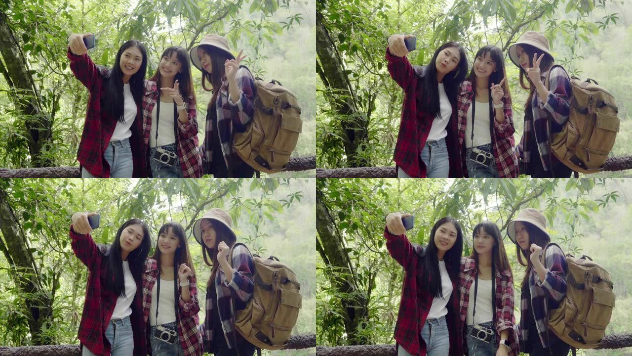 亚洲年轻女孩团体步行旅行自然女孩手持智能手机自拍自然背景看屏幕