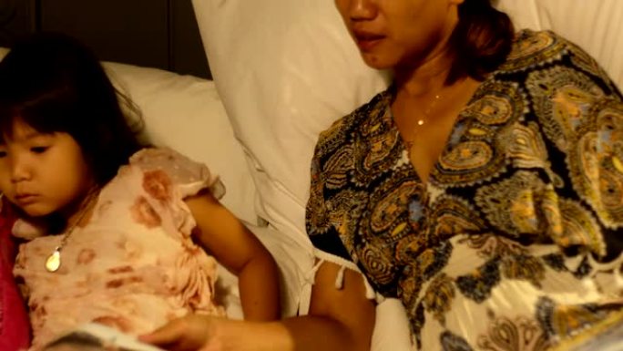 亚洲母亲给她的小女孩读睡前故事