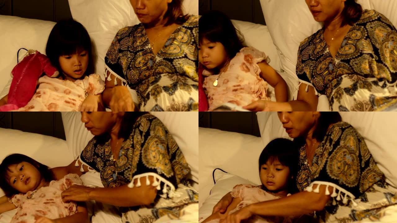 亚洲母亲给她的小女孩读睡前故事