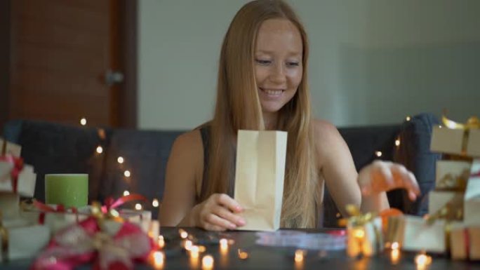 一个年轻女子正在打包礼物的慢镜头。在圣诞节或新年礼物中，用手纸包裹着红色和金色的缎带。女人为她的孩子