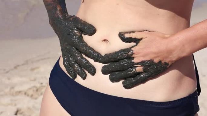 女孩用治疗性泥在肚子上留下手印，天然海水疗护肤品